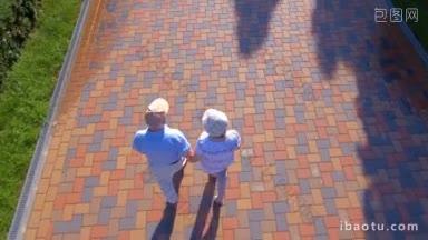 航拍的一对老年夫妇在夏日公园牵着手散步的画面